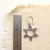 A feathered sun earring next to a ruler for size reference