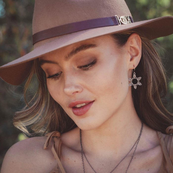 The feathered sun earrings being worn by a model