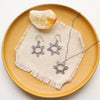 The feathered sun necklace styled on a yellow plate with the matching earrings