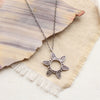 The feathered sun necklace styled on tan linen 