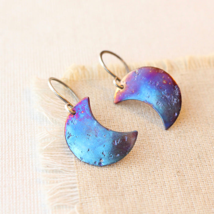 The fire painted moon earrings styled on tan linen