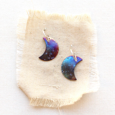 The fire painted copper moon earrings styled on tan linen