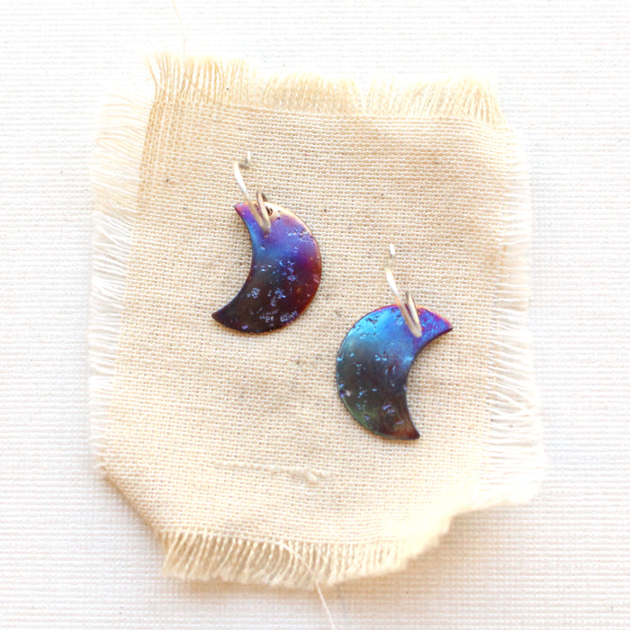 The fire painted copper moon earrings styled on tan linen