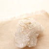 The gold floating heart earrings styled on a crystal