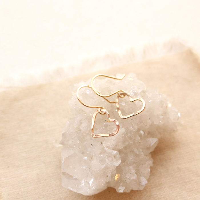 The gold floating heart earrings styled on a crystal