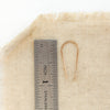 A gold hook earring next to a ruler for size reference