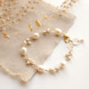 The gold pearl bud vine bracelet styled on tan line with dried grass