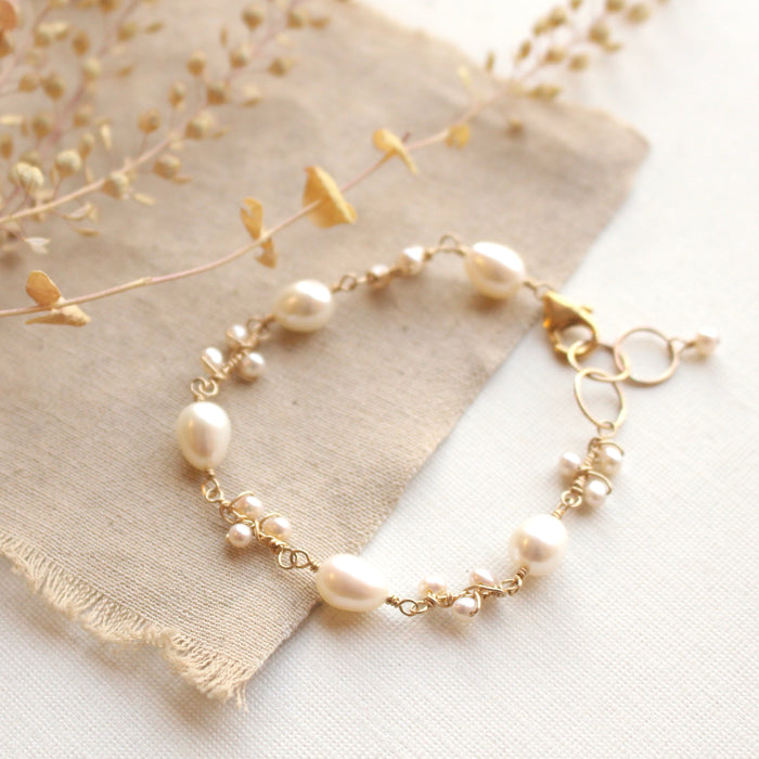 The gold pearl bud vine bracelet styled on tan line with dried grass