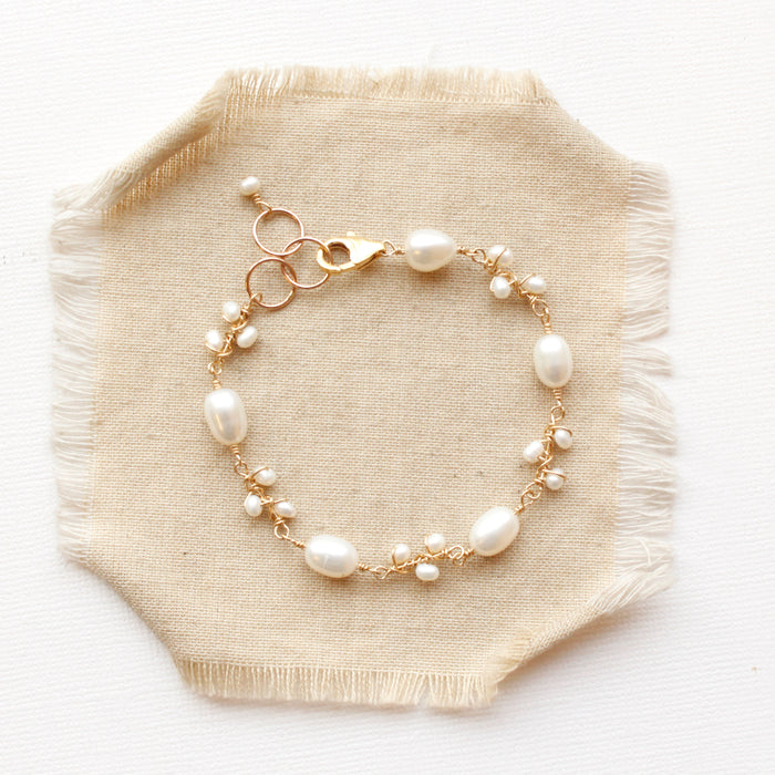 The gold pearl bud vine bracelet styled on tan linen