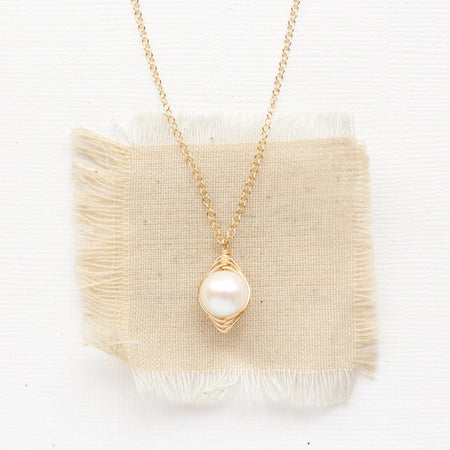 The perfect pearl gold necklace styled on tan linen