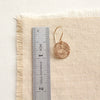 A raw silk disc earring next to a ruler for size reference