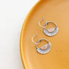 The happy half sun earrings styled on a yellow plate