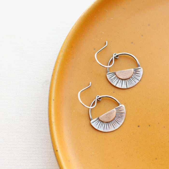 The happy half sun earrings styled on a yellow plate