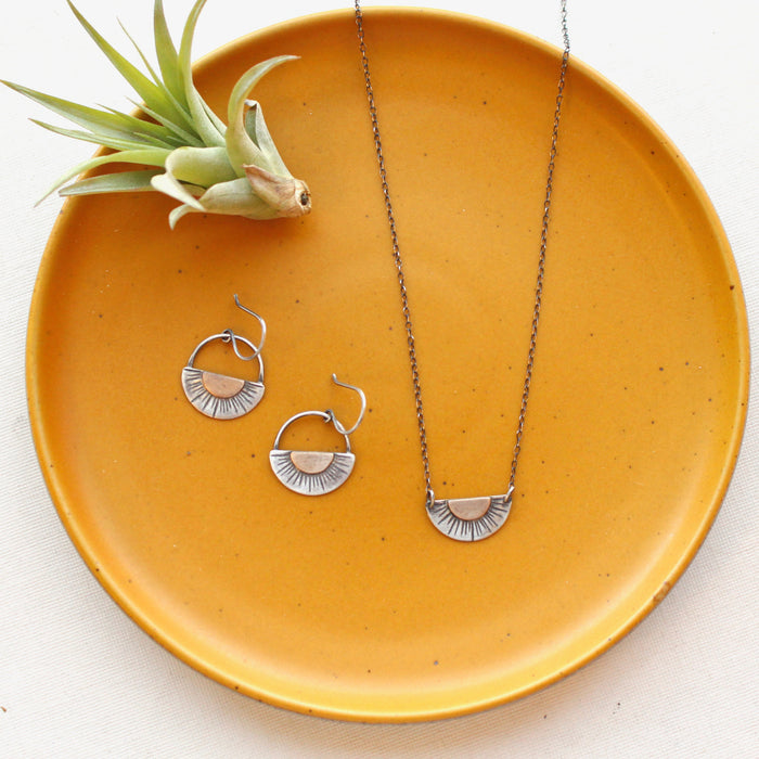 The happy half sun earrings styled on a yellow plate with the matching necklace