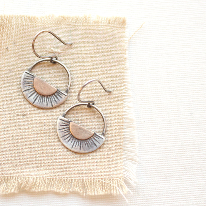 The happy half sun earrings styled on tan linen