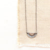 The happy half sun necklace styled on tan linen