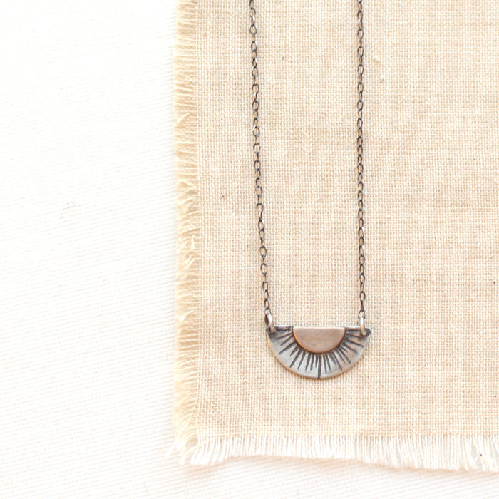 The happy half sun necklace styled on tan linen