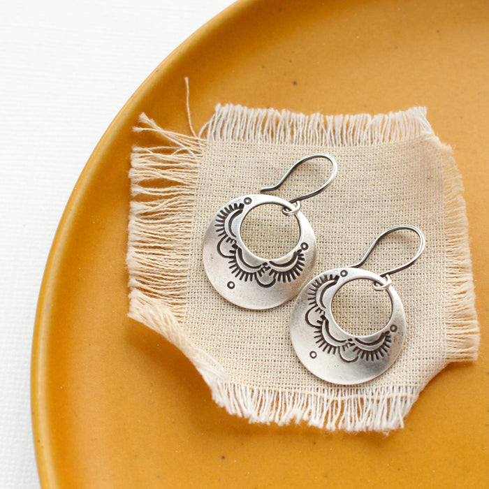 The jolie hoop earrings styled on a yellow plate with linen