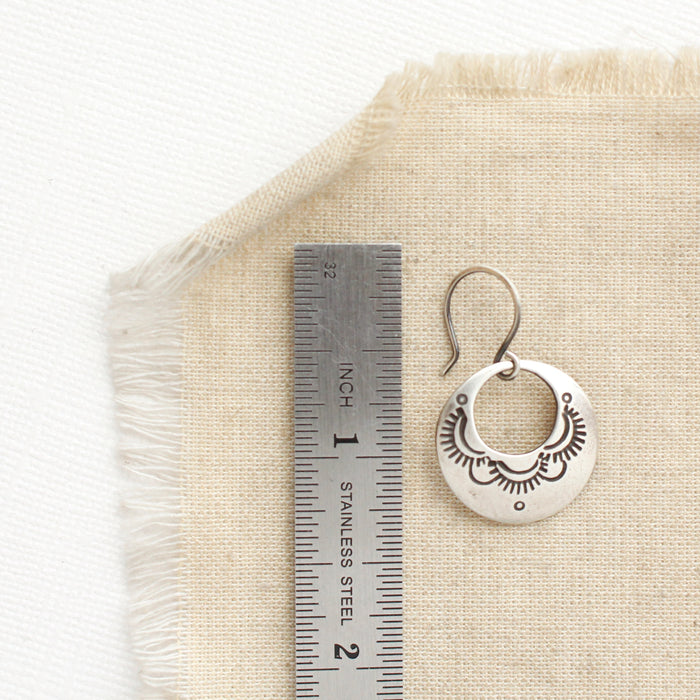 A jolie hoop earring next to a ruler for size reference