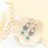 The jolie turquoise earrings styled on tan linen with dried grass