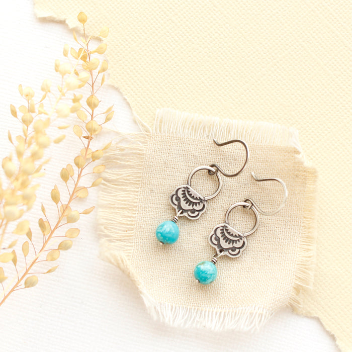 The jolie turquoise earrings styled on tan linen with dried grass