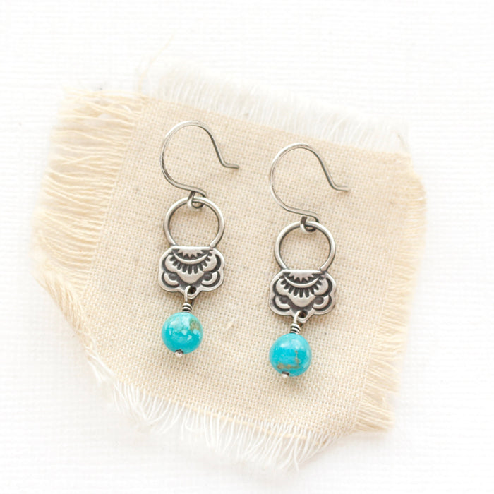 The turquoise jolie earrings styled on tan linen