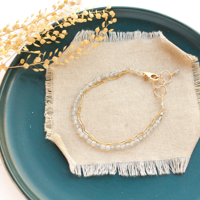 The labradorite double strand bracelet styled on a blue plate with linen and dried grass