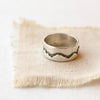 The layered silver mountain band ring styled on tan linen