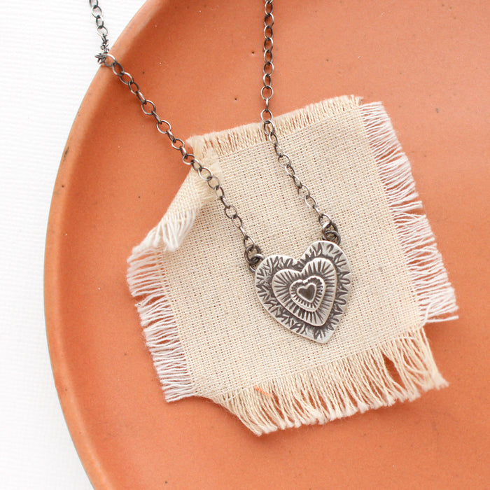 The layers of love necklace styled on an orange plate with linen