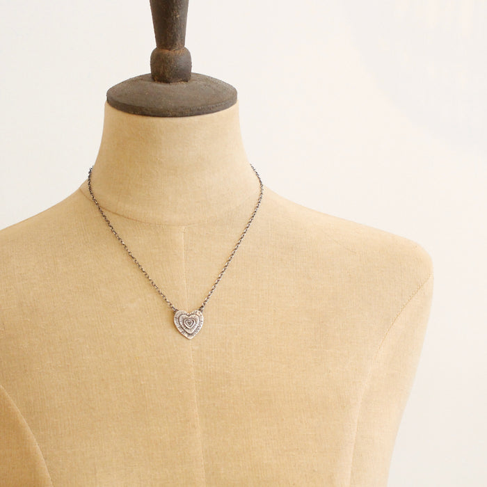 A mannequin wearing the layers of love heart necklace