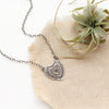 The layers of love necklace styled on tan linen with an air plant