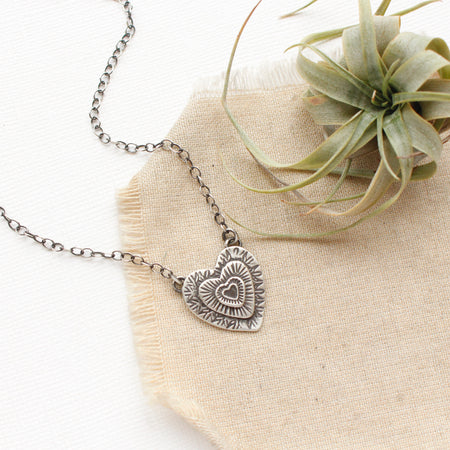 The layers of love necklace styled on tan linen with an air plant