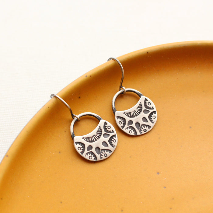 The midnight bloom earrings styled on a yellow plate