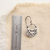 A midnight bloom earring next to a ruler for size reference