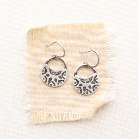 The midnight bloom earrings styled on tan linen