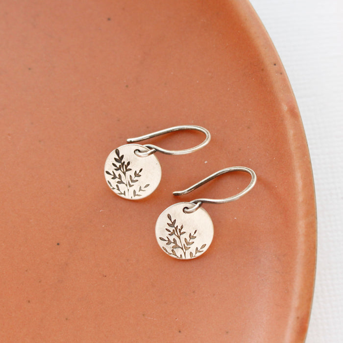The mini sprout earrings styled on an orange plate