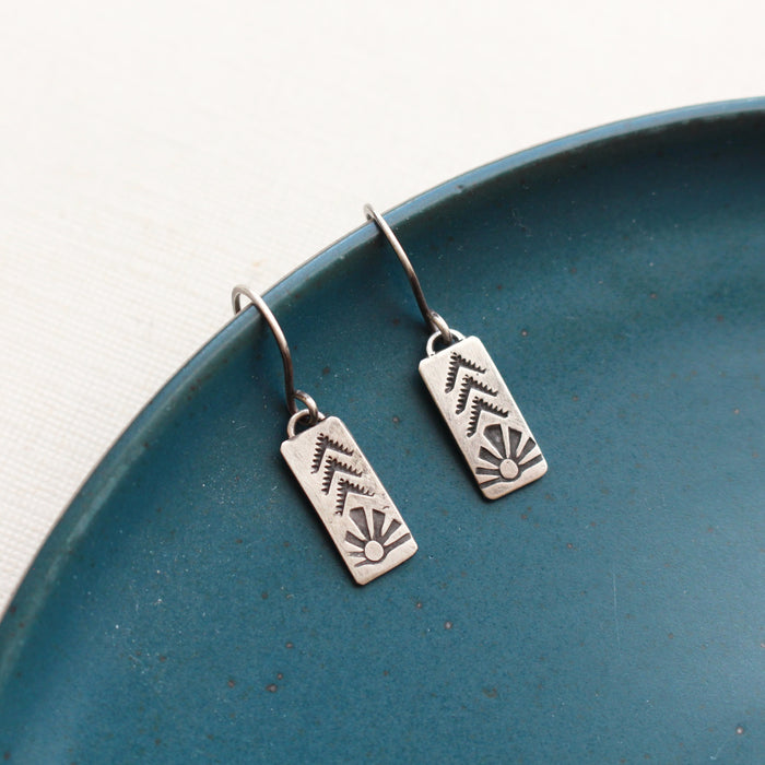 the mini sun bar earrings styled on a blue plate