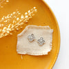 The mini talara post earrings styled on a yellow plate with linen and dried grass
