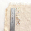 A labradorite wrapped mixed metal vine earring next to a ruler for size reference