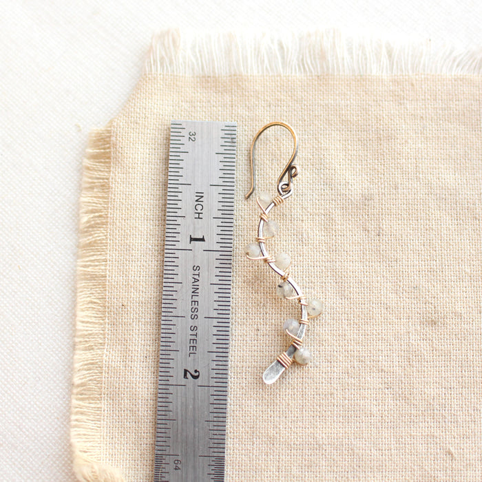 A labradorite wrapped mixed metal vine earring next to a ruler for size reference