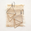 The mixed metal triple triangle hoop earrings styled on tan linen