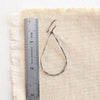 An oxidized silver forged teardrop hoop earring next to a ruler for size reference