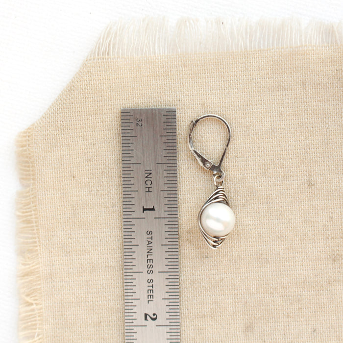 An oxidized silver perfect pearl earring next to a ruler for size reference