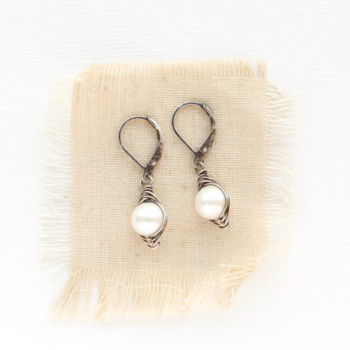 The oxidized silver perfect pearl earrings styled on tan linen