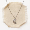 The pakal moon necklace styled on tan linen