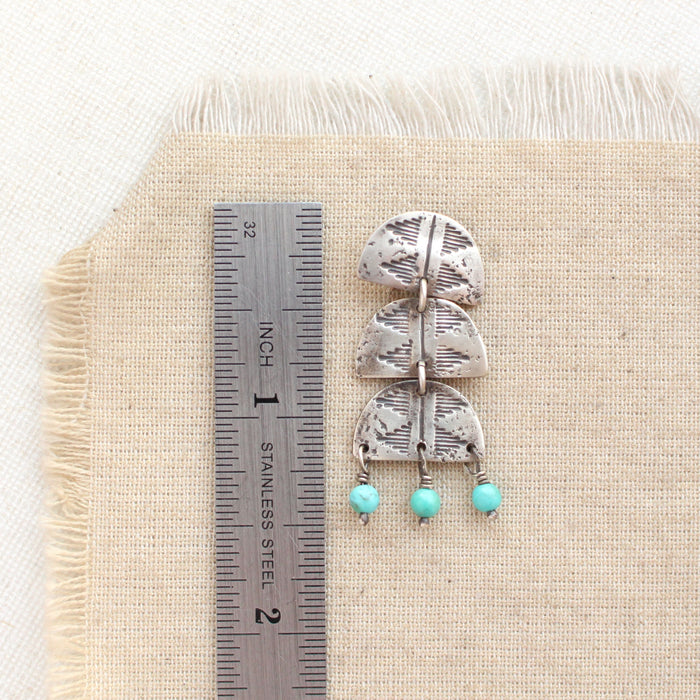 A pakal trio turquoise dangle post earring next to a ruler for size reference