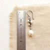 An oxidized silver pearl bud vine earring next to a ruler for size reference