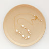 The gold wrapped pearl bud vine necklace styled on a tan plate to show the adjustable lobster clasp closure