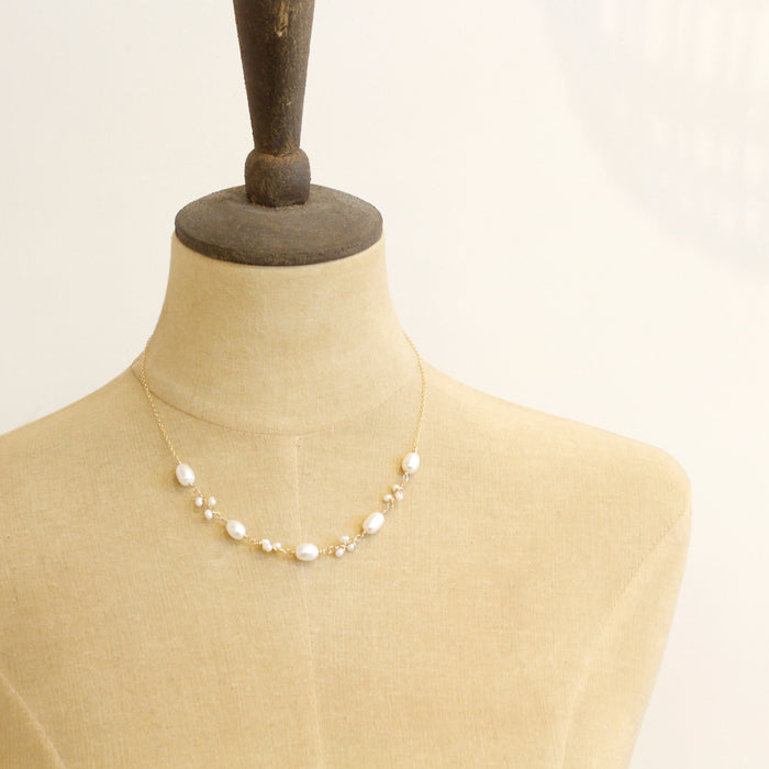 A mannequin wearing the gold wrapped pearl bud vine necklace
