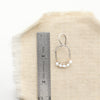 A pearl wrapped mixed metal hoop earring next to a ruler for size reference
